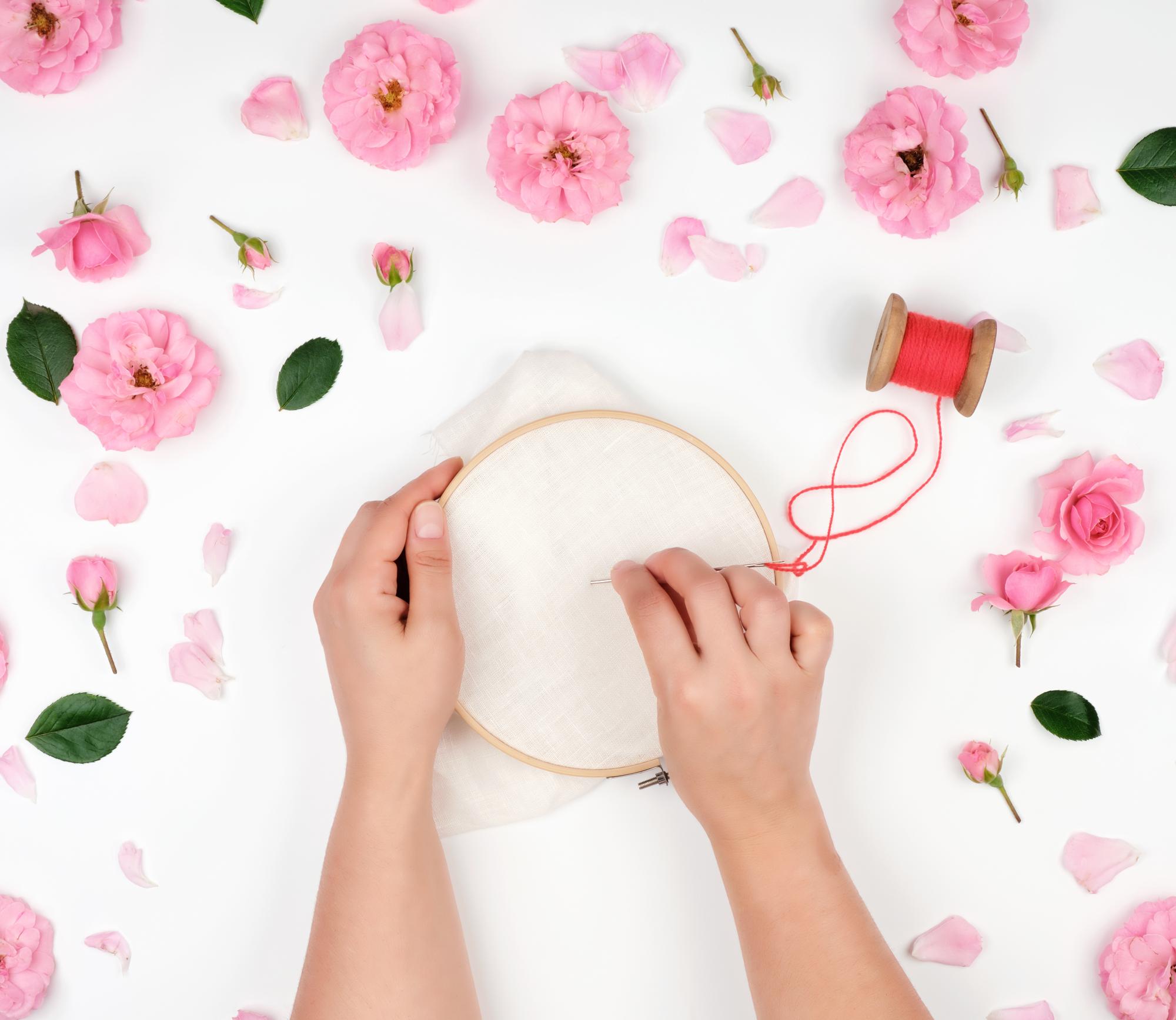 artisan's hands stitching a floral motif